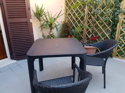 a black table and two chairs and some plants at Chiara Rooms in Rome