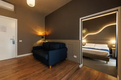 a bedroom with a bed and a chair and a mirror at Il Corso Comfort Rooms in Rome