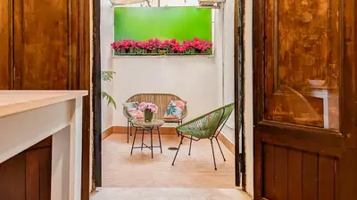 a room with two chairs and a table with pink flowers at Colosseum Charme Apartments in Rome