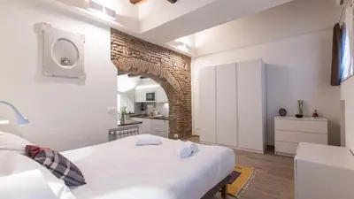 a bedroom with a white bed and a brick wall at Rental in Rome Trastevere White in Rome