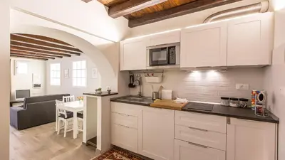 a kitchen with white cabinets and a living room at Rental in Rome Trastevere White in Rome