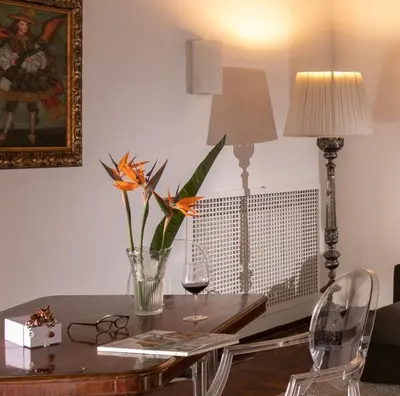 a table with a vase with a flower and a lamp at Riccardo Condotti Suite in Rome