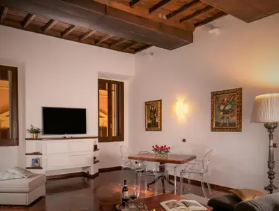 a living room with a table and a tv at Riccardo Condotti Suite in Rome