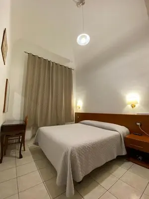 a bedroom with a bed and a table and a window at Hotel Il Papavero in Rome