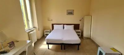 a bedroom with a bed with white sheets and two pillows at Villa Riari Garden in Rome
