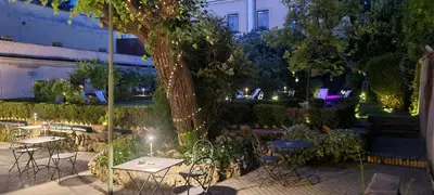 a garden with tables and chairs and a tree at night at Villa Riari Garden in Rome