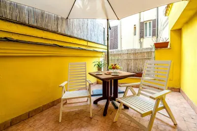 two chairs and a table with an umbrella on a patio at SmooRoomS Roma Ostiense in Rome