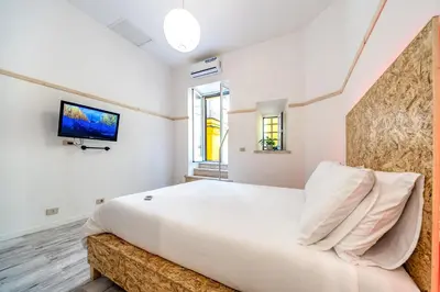 a bedroom with a large bed and a tv on the wall at SmooRoomS Roma Ostiense in Rome