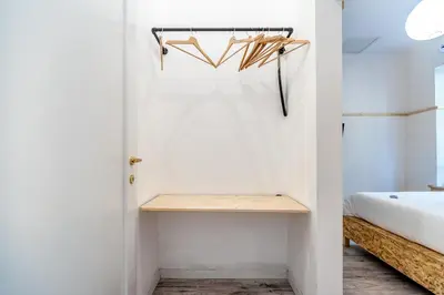 a room with a bed and a closet with a wooden shelf at SmooRoomS Roma Ostiense in Rome