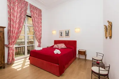 a bedroom with a red bed and a large window at Prestigious Apartment via Barberini in Rome