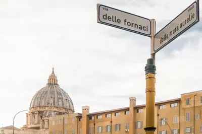 a pole with two street signs in front of a building at Be Rome in Rome
