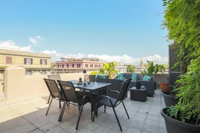 a patio with a table and chairs on a roof at Colosseo Apartment Holiday - Attico al Colosseo a Monti in Rome