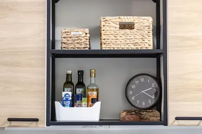 a shelf with bottles of wine and a clock at Colosseo Apartment Holiday - Attico al Colosseo a Monti in Rome