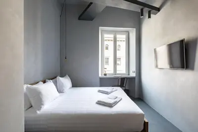 a bedroom with a bed with white sheets and a television at Pietra - The Italian Stay Collection in Rome