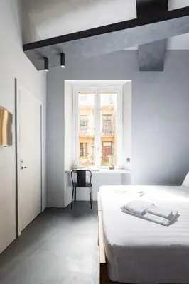a white bedroom with a bed and a chair at Pietra - The Italian Stay Collection in Rome