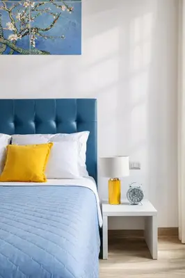 a bed with a blue headboard and a table with a lamp at Urbana 37 Maison - Rione Monti by RHR in Rome