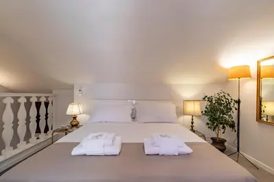 a bedroom with a large white bed with two towels at Palazzo storico Dormo da Lisa - Colosseo in Rome