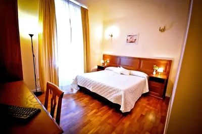a bedroom with a bed and a desk and a window at Relais Cavour in Rome