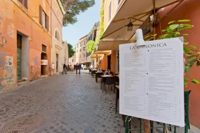 a sign on the side of a street with tables and chairs at Il Leopardo (Trastevere) in Rome