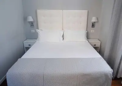 a bed with white sheets and pillows in a bedroom at Relais Villa Coppedè in Rome