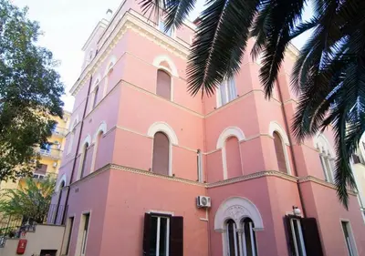 a pink building with a palm tree in front of it at Relais Villa Coppedè in Rome