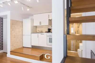 a kitchen with white cabinets and a wooden floor at Residenza Gonfalone in Rome