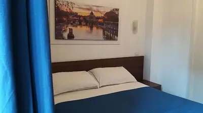 a bed in a room with a blue curtain and a painting at Roma My Home B&B in Rome