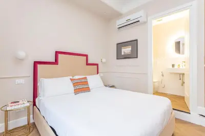 a white bedroom with a white bed with a red headboard at Rome Central Inn in Rome