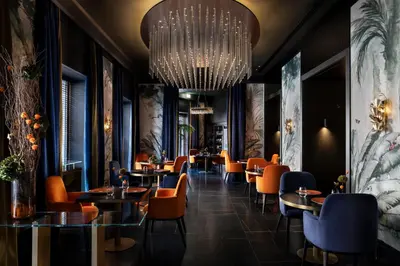 a restaurant with orange chairs and tables and a chandelier at The Pantheon Iconic Rome Hotel, Autograph Collection in Rome