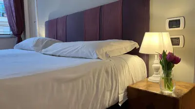a bed with a vase of flowers on a table with a lamp at NTB Roma B&B in Rome