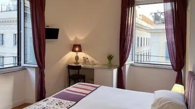 a bedroom with a bed and a desk and windows at NTB Roma B&B in Rome