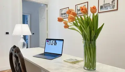 a vase of orange tulips sitting on a table with a laptop at NTB Roma B&B in Rome
