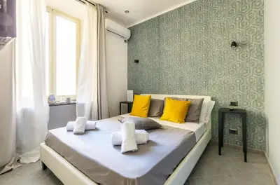 a bedroom with a large bed with yellow pillows at Merulana 139 Suites in Rome