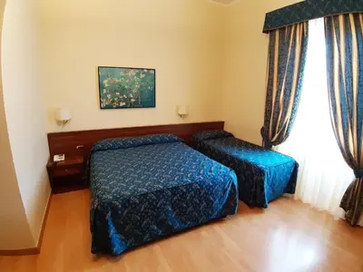 a hotel room with two beds and a window at Colosseo Roma in Rome