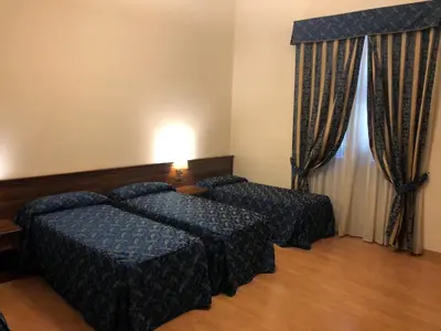 a hotel room with two beds and a window at Colosseo Roma in Rome