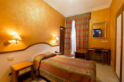 a hotel room with a bedroom with a bed and a table at Hotel Lella in Rome