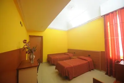 a room with two beds in a yellow room at Hotel Lella in Rome