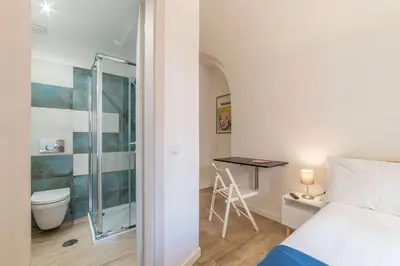 a bedroom with a bed and a bathroom with a table at Roma Station House in Rome