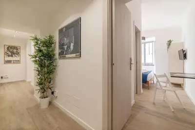 a white hallway with a table and a plant at Roma Station House in Rome
