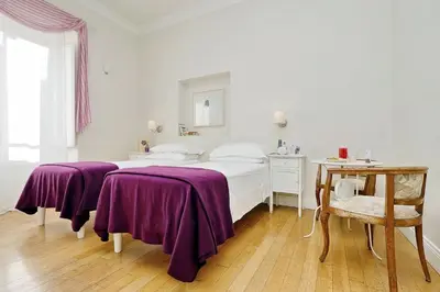 a white bedroom with two beds with purple blankets at Guest House Amaranto Romano in Rome