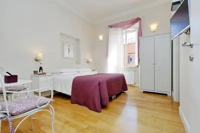 a white bedroom with a bed and a table and chairs at Guest House Amaranto Romano in Rome