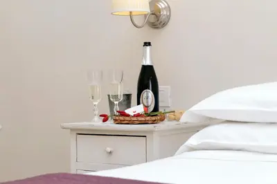 a bedside table with a bottle of wine and glasses at Guest House Amaranto Romano in Rome