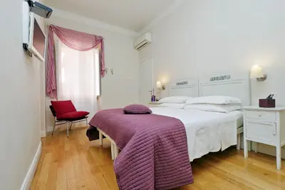 a bedroom with a large white bed and a red chair at Guest House Amaranto Romano in Rome