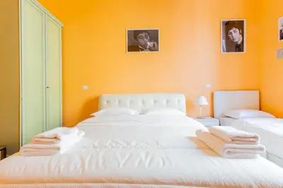 a large white bed in a room with orange walls at Flower guesthouse in Rome