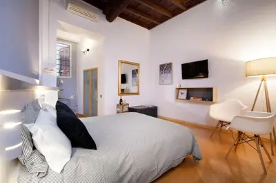 a white bedroom with a bed and a desk and chair at Delle Grotte Apartment in Rome