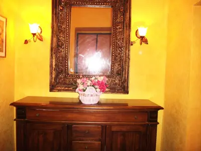 a mirror on top of a wooden dresser with flowers at Max House in Rome