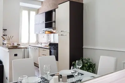 a kitchen with a dining table and white chairs at Frattina Royal in Rome