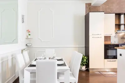 a white kitchen with a white table and chairs at Frattina Royal in Rome