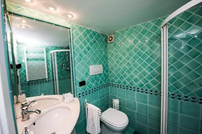 a green tiled bathroom with a sink and a toilet at AmoRoma Francesca in Rome