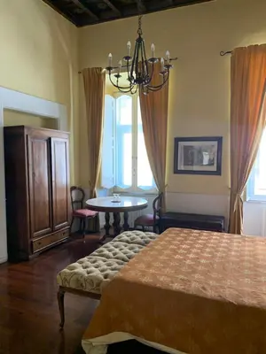 a bedroom with a bed and a table and windows at Relais Teatro Argentina in Rome